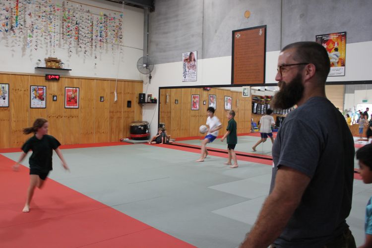 Coach supervising a group of neurodivergent kids, including those with ADHD and autism, playing a fitness game in the dojo at Functional Fitness Eltham.