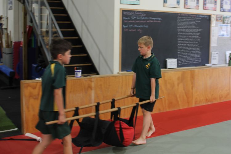Two neurodivergent kids working together to carry a weighted bag during an NDIS-funded functional fitness class at Functional Fitness Eltham.