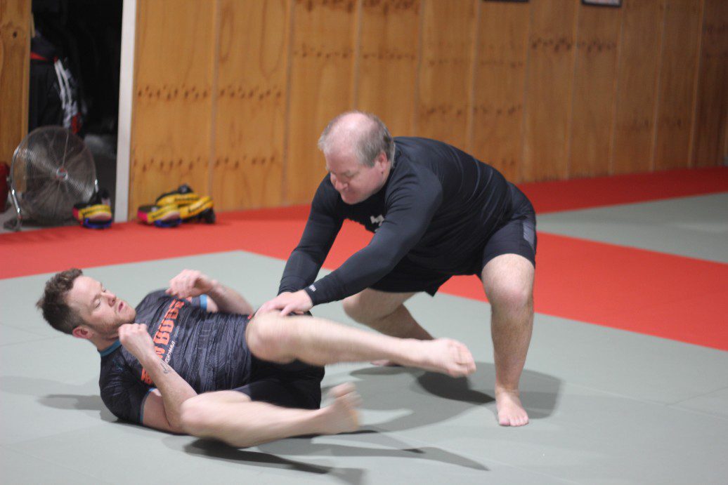 two students at Eltham Martial Arts Academy practicing ground defense techniques during a self-defence class, showcasing practical grappling training..jp